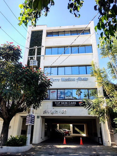 Dentista infantil en España - Un edificio blanco de cuatro plantas con grandes ventanales, vegetación en la fachada y un letrero en el que se lee Torre Médica Abeto. Encima de la entrada, que conduce a una zona de aparcamiento, se ve una pancarta de la clínica Top Skin Care y un cartel de odontopediatra en León. Los árboles enmarcan la escena. | Clínica dental pediátrica Dentistainfantilcercademi