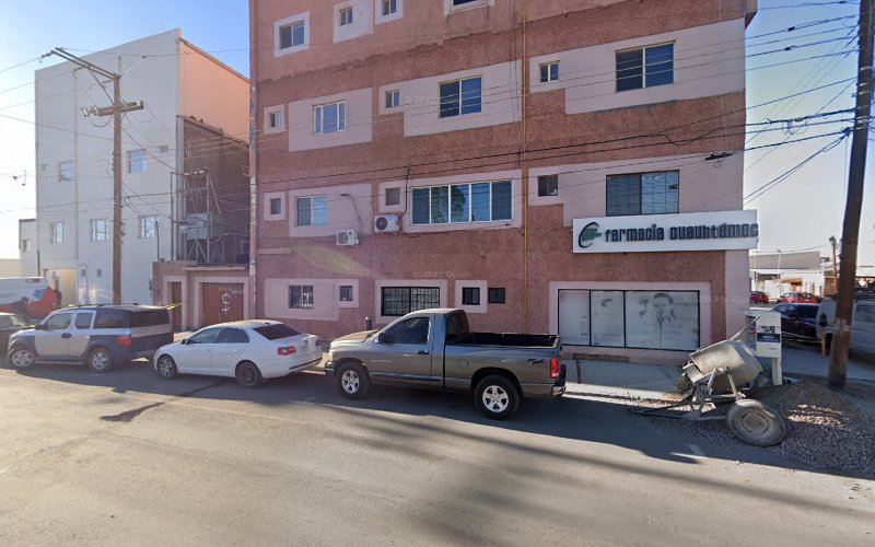 Dentista infantil en España - Vista de la calle de un edificio de cuatro plantas con un letrero en el que se lee Farmacia Cuauhtémoc. Varios vehículos aparcados, incluidos coches y una camioneta, se alinean en la calle frente al edificio en un día soleado. | Clínica dental pediátrica Dentistainfantilcercademi