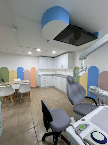 Dentista infantil en España - Una moderna consulta dental con paredes en tonos pastel, un sillón dental, equipos médicos, armarios blancos y un escritorio con sillas blancas sobre un suelo de baldosas marrón claro. | Clínica dental pediátrica Dentistainfantilcercademi