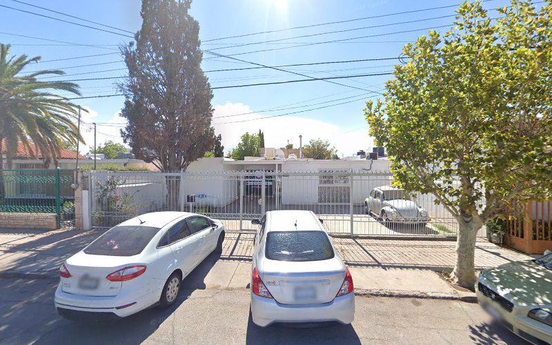 Dentista infantil en España - Dos coches blancos están aparcados en una calle tranquila delante de una casa blanca de una sola planta con árboles y acera. El cielo está despejado y soleado. | Clínica dental pediátrica Dentistainfantilcercademi