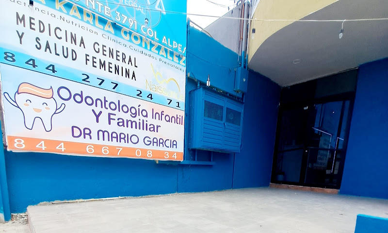Dentista infantil en España - Exterior de un edificio azul con dos carteles; uno anuncia servicios de salud general y de la mujer, y el otro promociona la odontopediatría y odontología familiar del Dr. Mario García, odontopediatra en Saltillo. A la derecha se ve una entrada con puerta de cristal. | Clínica dental pediátrica Dentistainfantilcercademi