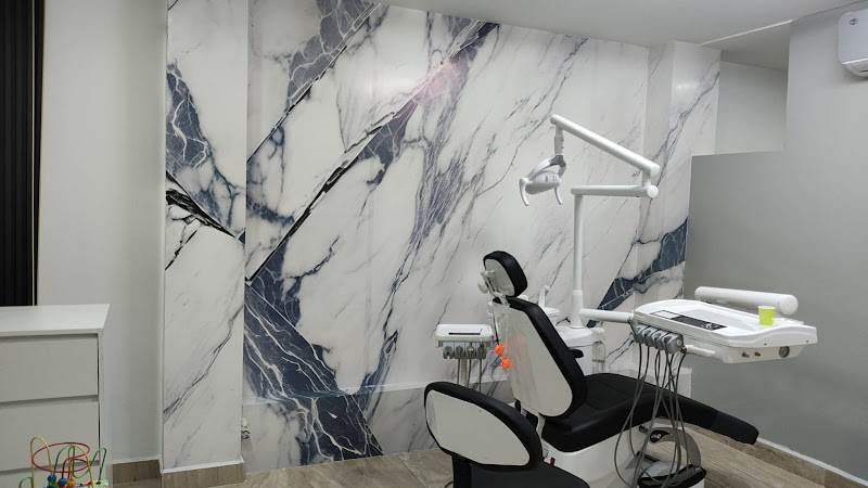 Dentista infantil en España - Una moderna sala de clínica dental con una pared de mármol blanco y negro, sillón dental, luz cenital, instrumental dental y un pequeño armario lateral. La sala está limpia y bien iluminada. | Clínica dental pediátrica Dentistainfantilcercademi