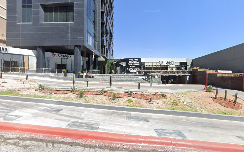Dentista infantil en España - Una moderna plaza comercial con restaurantes y tiendas, que incluye carteles de Kokumi, Toscana y Wehot Office. Hay escaleras, jardineras con pequeñas plantas y una zona de aparcamiento frente a los edificios. | Clínica dental pediátrica Dentistainfantilcercademi