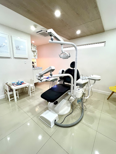 Dentista infantil en España - Una consulta dental moderna y limpia con un sillón de dentista negro, equipo dental y luz cenital. La sala tiene paredes blancas, suelos de baldosas y una pequeña mesa para niños con juguetes y libros en un rincón. | Clínica dental pediátrica Dentistainfantilcercademi
